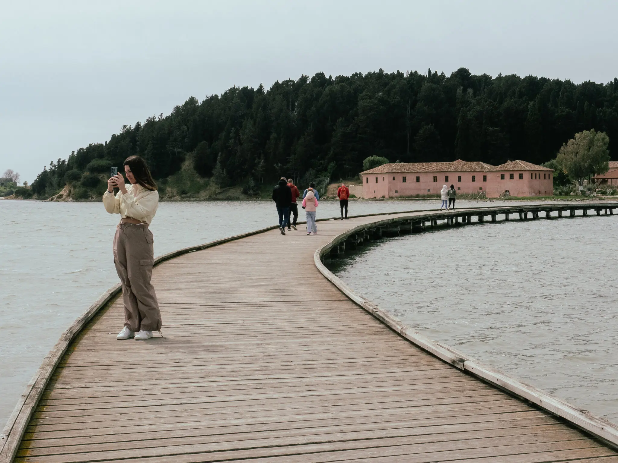 Туристи на набережній, що веде до Св. Марії, візантійського монастиря XIII століття, побудованого на маленькому острові в лагуні Нарта.